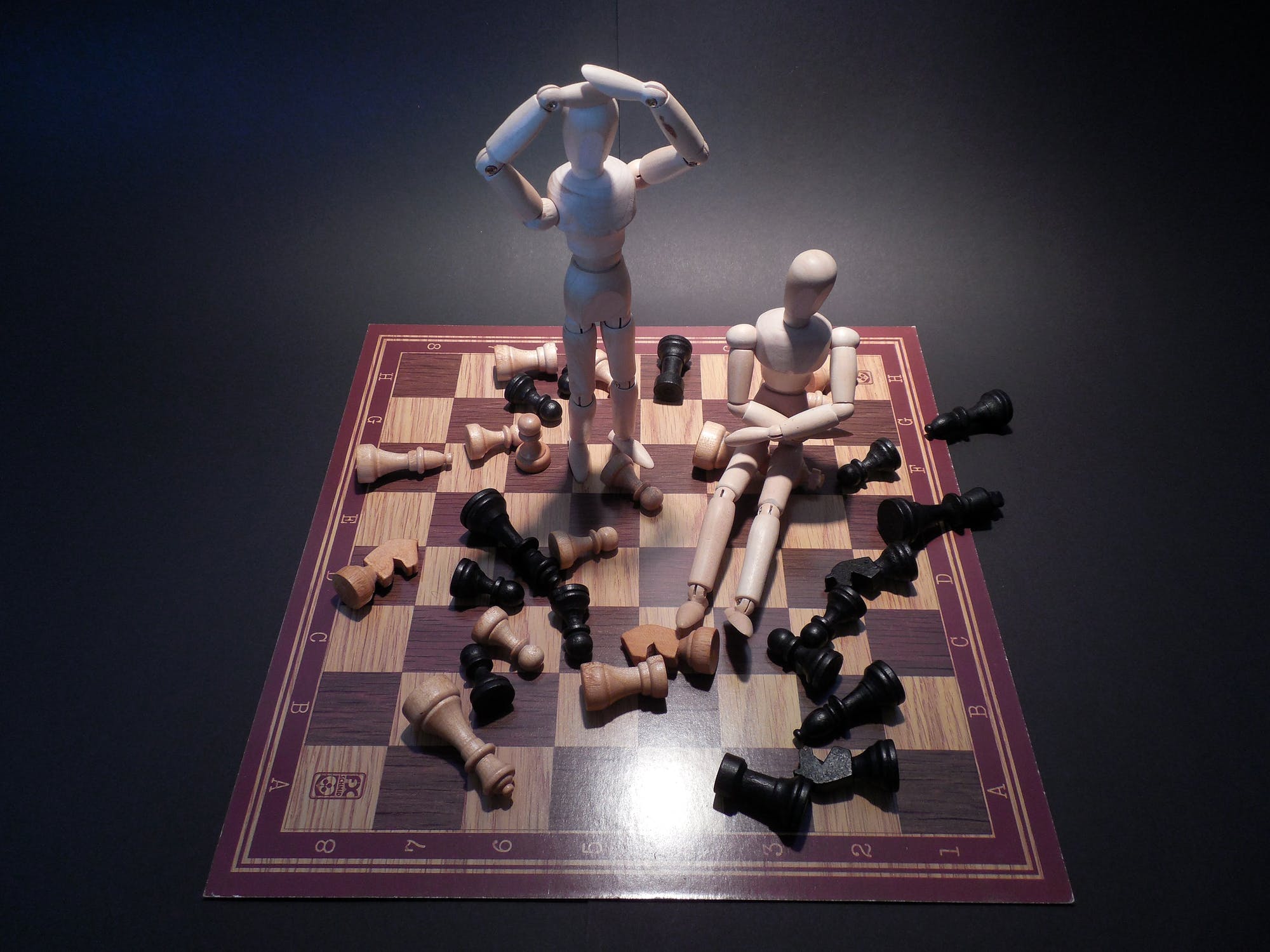 Human figures playing chess on a chess board.